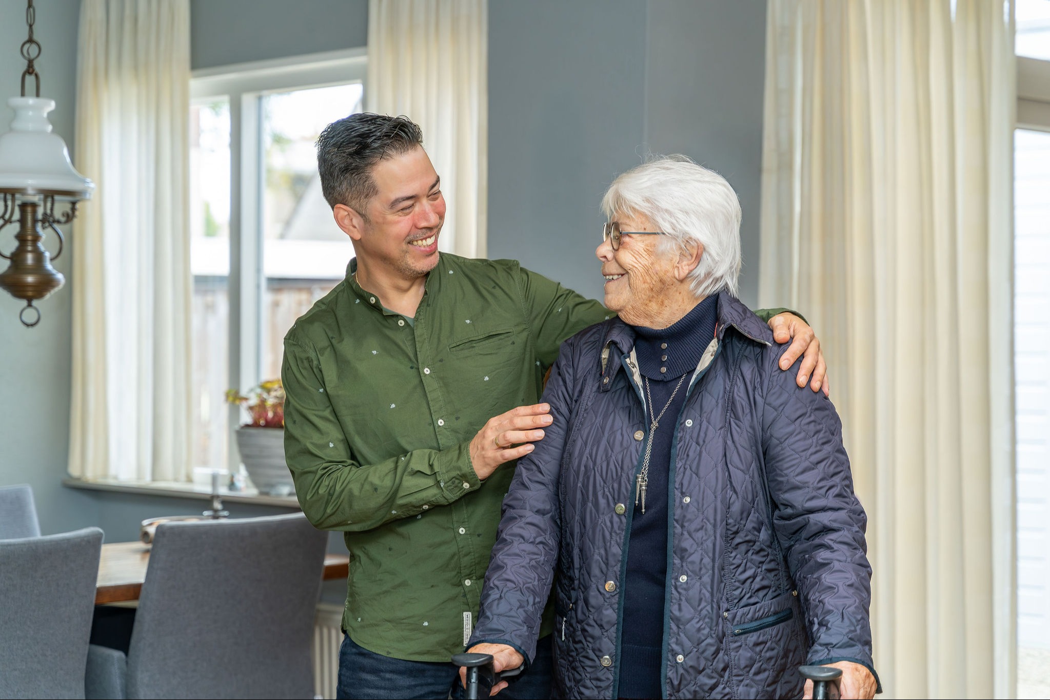Wijkverpleegkundige en oudere mevrouw kijken naar elkaar